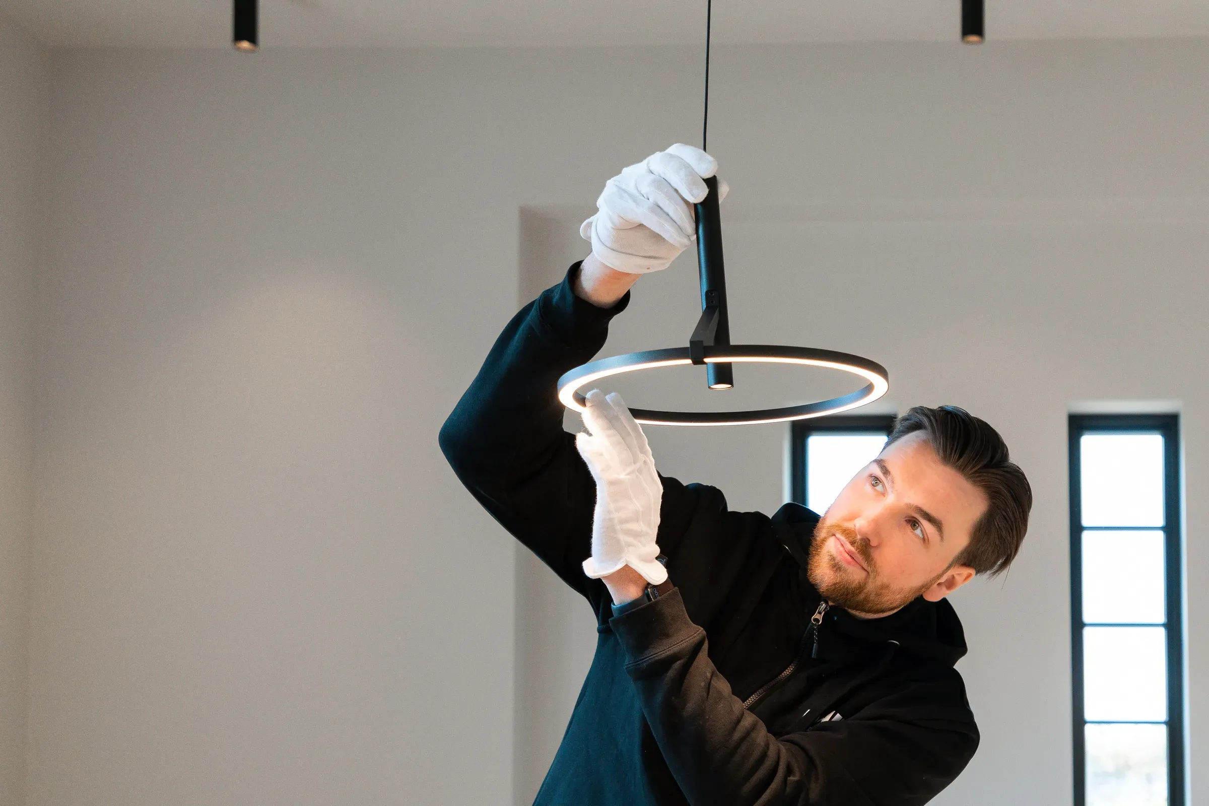 Elektriker med hvite hansker monterer taklampe trafohus