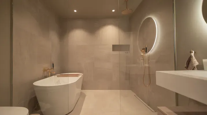 Moderne bad med frittstående badekar, rund speil med lys, dusj og minimalistisk interiør.