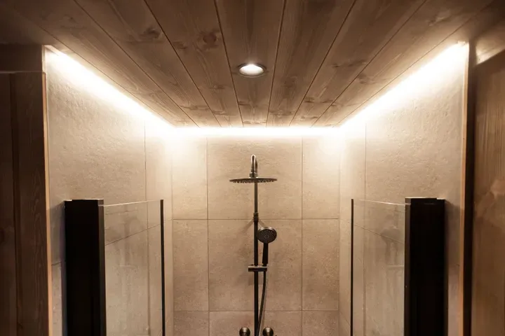 Dusj med moderne belysning i taket og flislagte vegger.