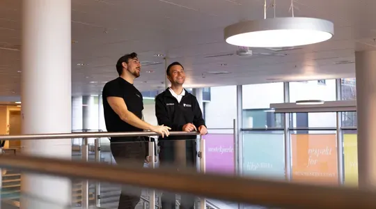 To elektrikere i et av fellesområdene ved Kirkeparken vgs, der belysning er levert av Team Installasjon.