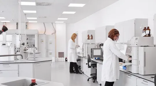 Et laboratorie med to personer i hvit frakk som arbeider