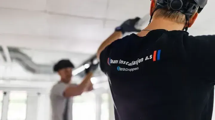 To elektrikere fra Team Installasjon arbeider med kabelføring i tak.