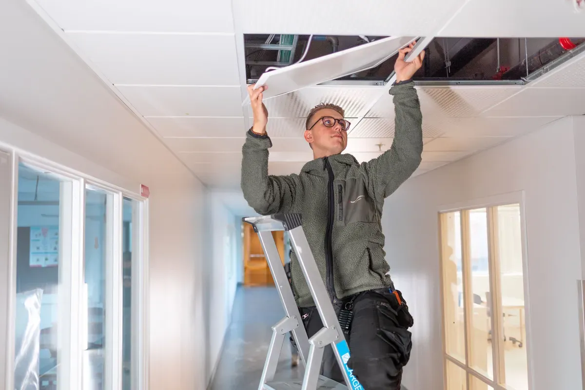 Elektriker i arbeid ved Kirkeparken vgs, der belysning er levert av Team Installasjon.