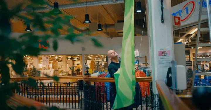 Person som henger opp et grønt banner i et kjøpesenter