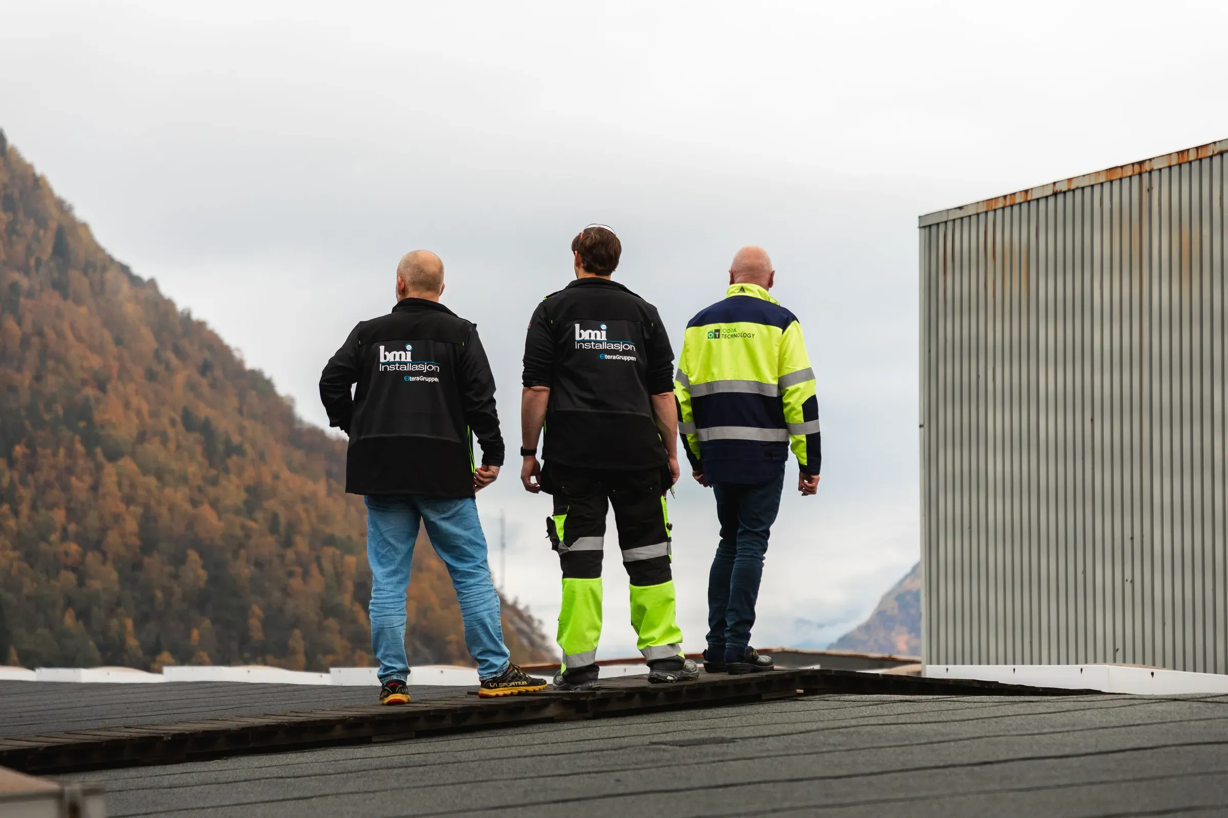 To ansatte hos BMI på toppen av taket, sammen med kunde