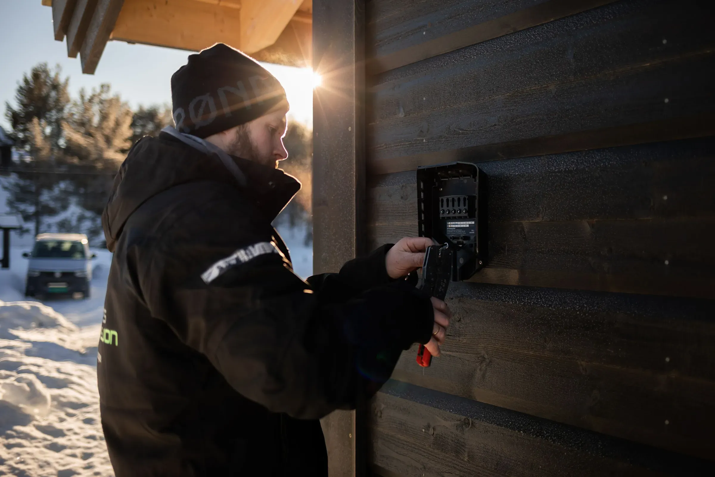 en Valdres installasjons ansatt som kobler opp en elbillader på en husvegg