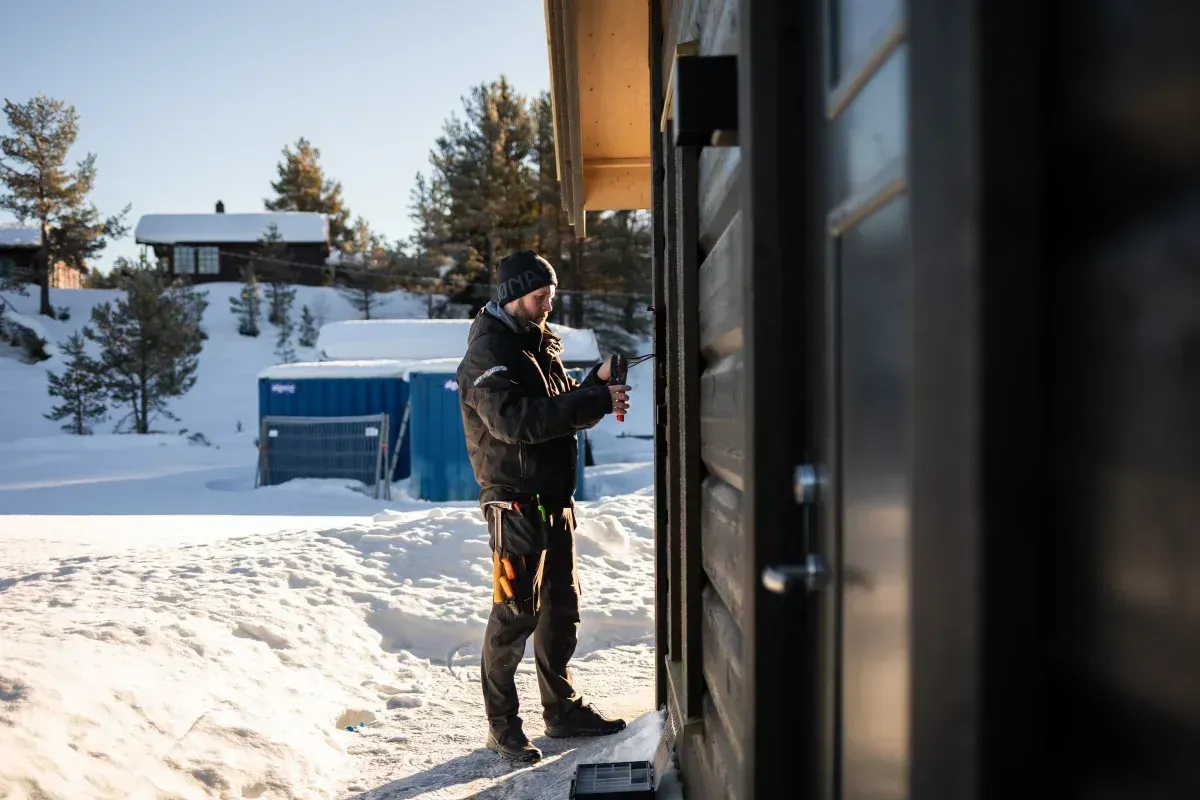 en Valdres Installasjons ansatt som installerer en elbillader på en husvegg